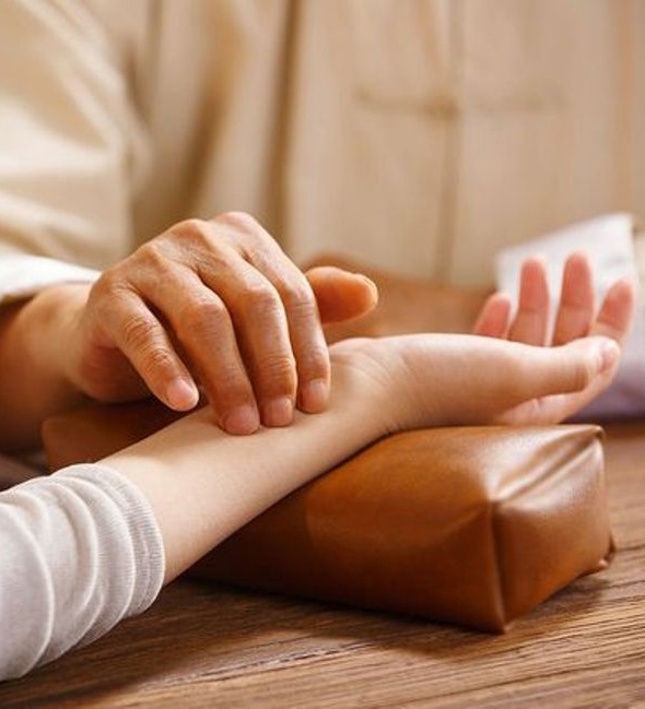 A practitioner gently assessing a pulse at the wrist